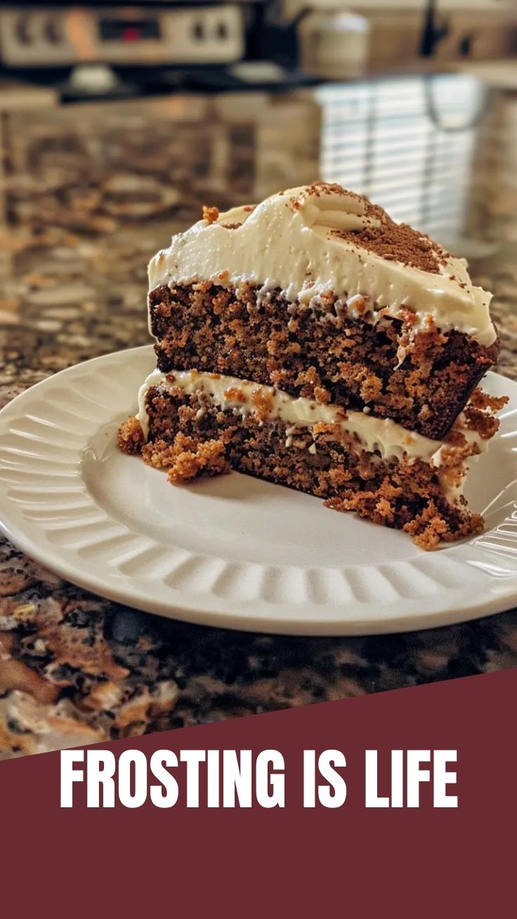 A delicious slice of carrot cake topped with generous cream cheese frosting.