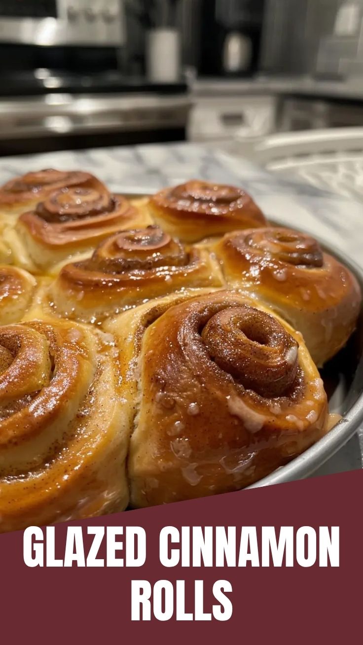 A tray of gooey homemade cinnamon rolls with white icing, fresh from the oven.